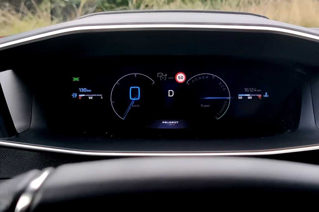 Ekran cyfrowych zegarów Peugeota 2008 Cyfrowy zestaw wskaźników samochodu Peugeot z prędkościomierzem, licznikiem przebiegu, wskaźnikiem poziomu paliwa oraz ikonami informacyjnymi, wszystko podświetlone i czytelnie rozmieszczone w kokpicie.