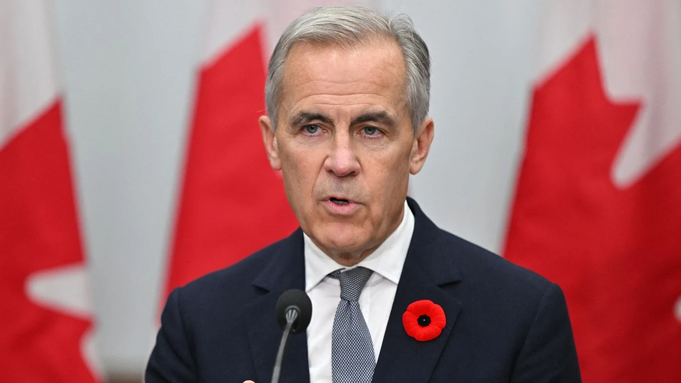 Premier Kanady Mark Carney przeprosił prezydenta USA Donalda Trumpa Mężczyzna w garniturze przemawia do mikrofonu, w tle widoczne są flagi Kanady. Na klapie marynarki przypięty czerwony mak.