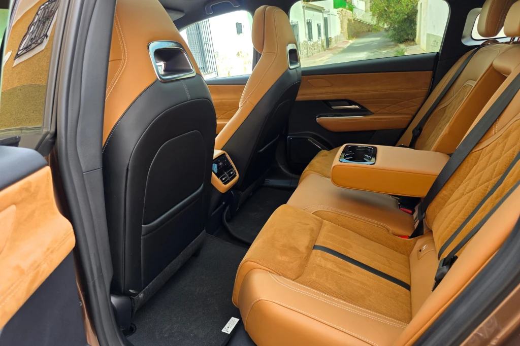 Tylny przedział bez trudu pomieści dwójkę dorosłych pasażerów; więcej światła w kabinie zapewnia standardowy dach panoramiczny Luksusowe wnętrze samochodu z brązowymi, skórzanymi siedzeniami, składanym podłokietnikiem na tylnej kanapie oraz nowoczesnym panelem wentylacji dla pasażerów z tyłu.