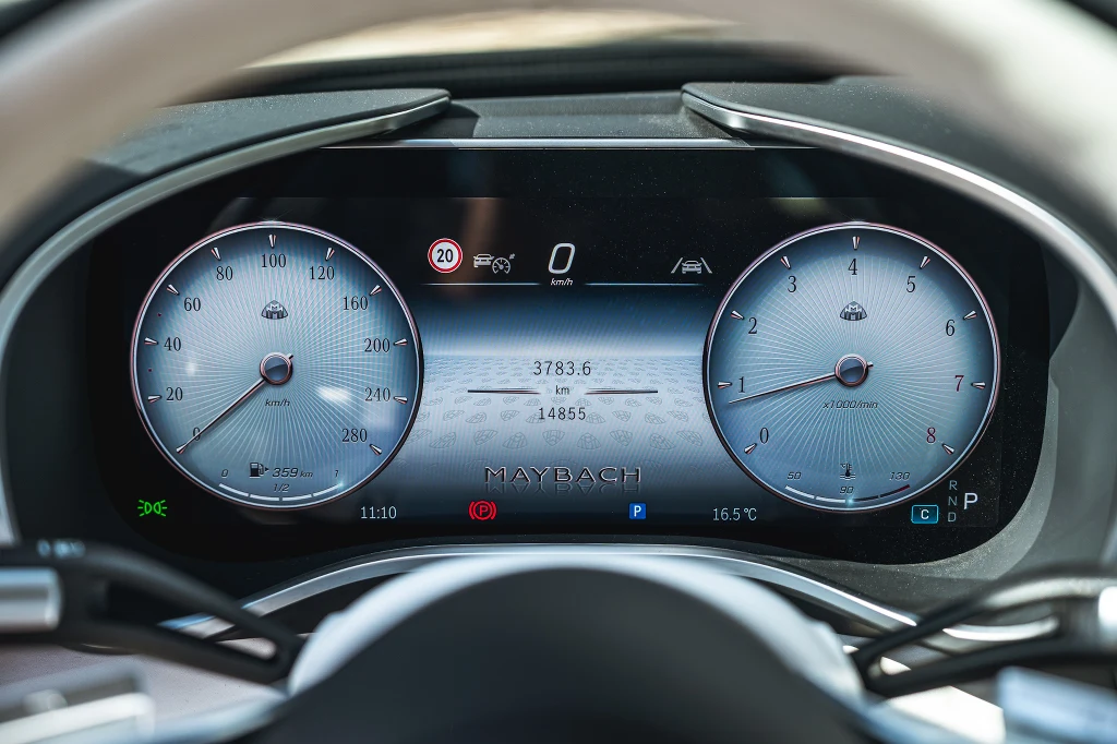 Cyfrowy kokpit samochodu marki Maybach z wyświetlanymi wskaźnikami prędkości, obrotów silnika oraz dodatkowymi informacjami o przebiegu, temperaturze zewnętrznej i poziomie paliwa.