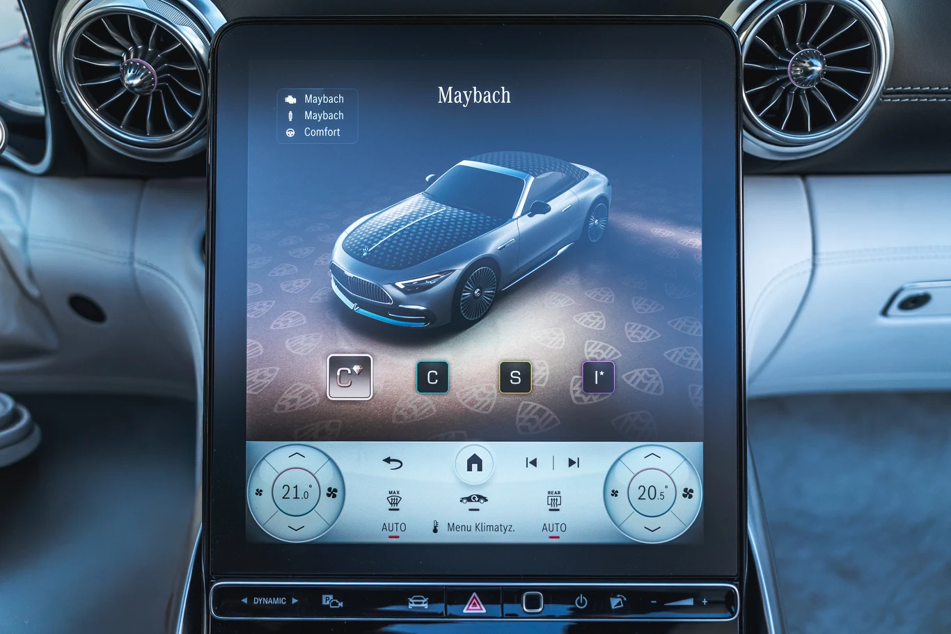 Duży wyświetlacz systemu multimedialnego w luksusowym samochodzie pokazuje wizualizację modelu Maybach oraz różne opcje sterowania komfortem, klimatyzacją i trybami jazdy. Wnętrze auta utrzymane jest w eleganckim, nowoczesnym stylu.
