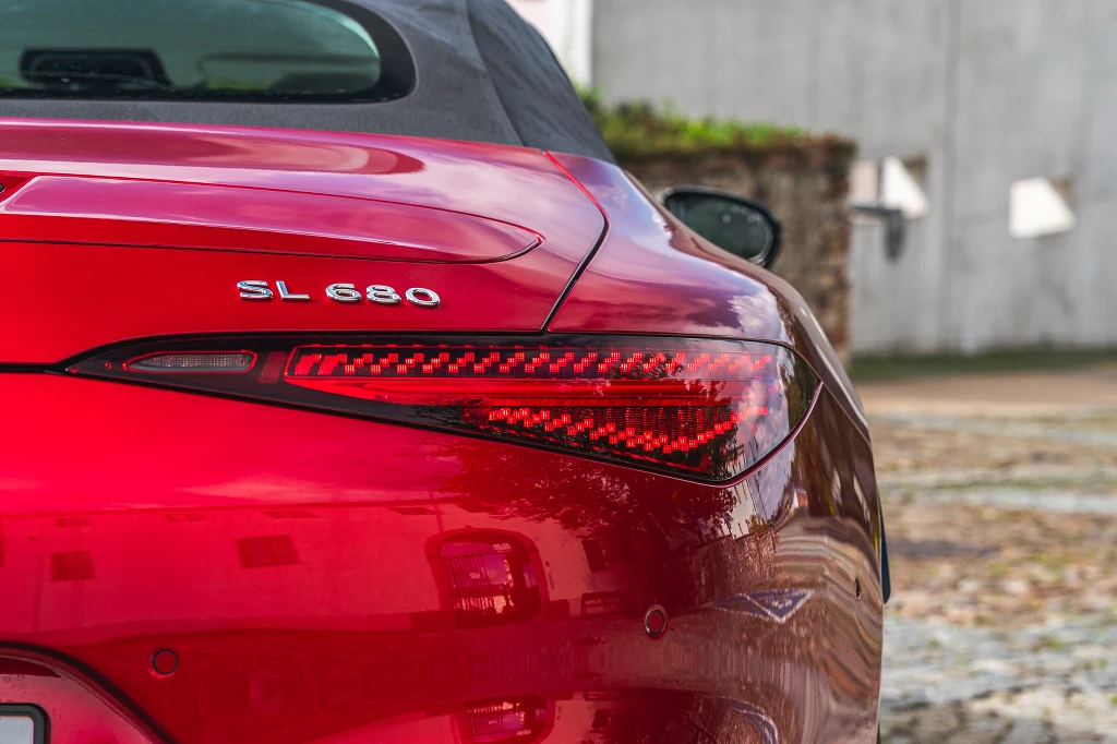 Czerwony samochód klasy premium, model Mercedes SL 680, ukazany z tyłu, wyraźnie widoczny nowoczesny tylny reflektor LED oraz oznaczenie modelu, w tle rozmyta ściana budynku.