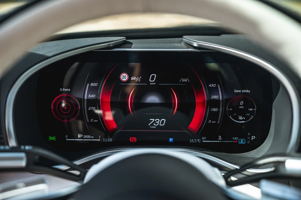 Cyfrowy, kolorowy wyświetlacz prędkościomierza i obrotomierza w nowoczesnym samochodzie sportowym z wyraźnie zaznaczonymi wskaźnikami prędkości, przełożeń i sił G.