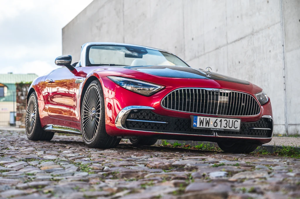 Czerwony kabriolet sportowy zaparkowany na brukowanej nawierzchni, ujęcie z niskiej perspektywy podkreśla masywny grill oraz dynamiczne linie nadwozia, z widoczną rejestracją WW 613UC.