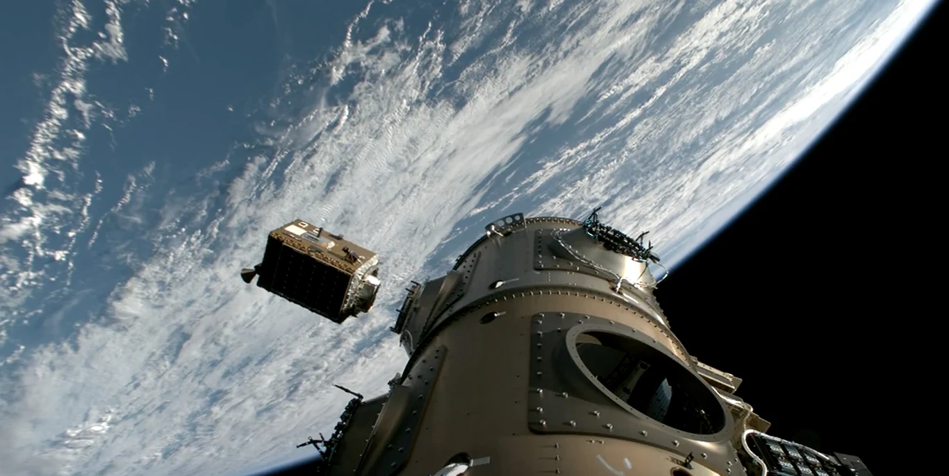 Haven Demo na orbicie. Pierwsza prywatna stacja kosmiczna blisko. Kapsuła kosmiczna unosząca się nad Ziemią w przestrzeni kosmicznej, na tle widoczna krzywizna planety pokrytej warstwą chmur, a obok kapsuły oddzielający się satelita.