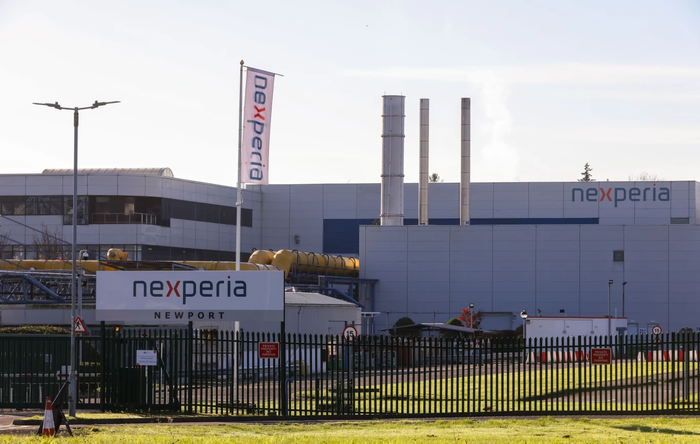 Chiny zezwolą na wyjątki od zakazu eksportu chipów Nexperia Nowoczesny zakład przemysłowy z widocznymi trzema kominami, dużymi panelami ściennymi oraz oznakowaniem firmy Nexperia na budynku, tablicy i fladze, całość ogrodzona metalowym płotem.