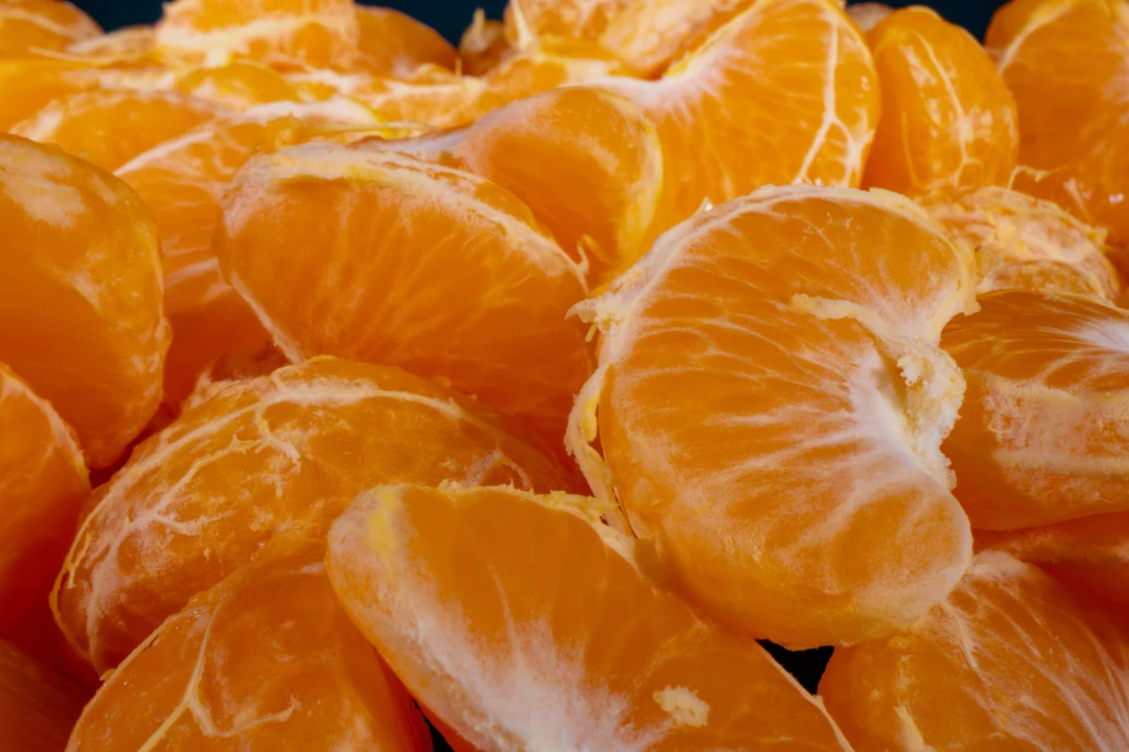 Soczyste mandarynki to uwielbiany przysmak. Nie każdemu jednak wyjdzie na zdrowie Soczyste cząstki mandarynek o intensywnie pomarańczowym kolorze ułożone blisko siebie, delikatnie pokryte błoną, podkreślające świeżość i apetyczność owoców.