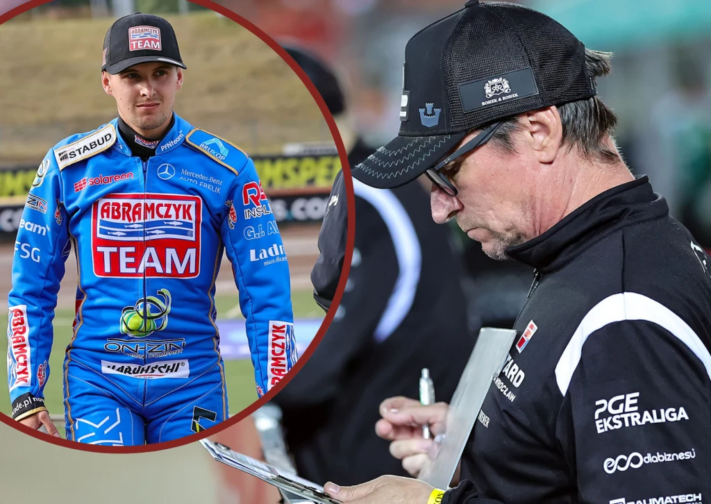 Żużlowiec ubrany w niebieski kombinezon z logotypami sponsorów stoi na stadionie, z boku widoczny jest trener zapisujący notatki na kartce, obaj skupieni na wydarzeniach sportowych.