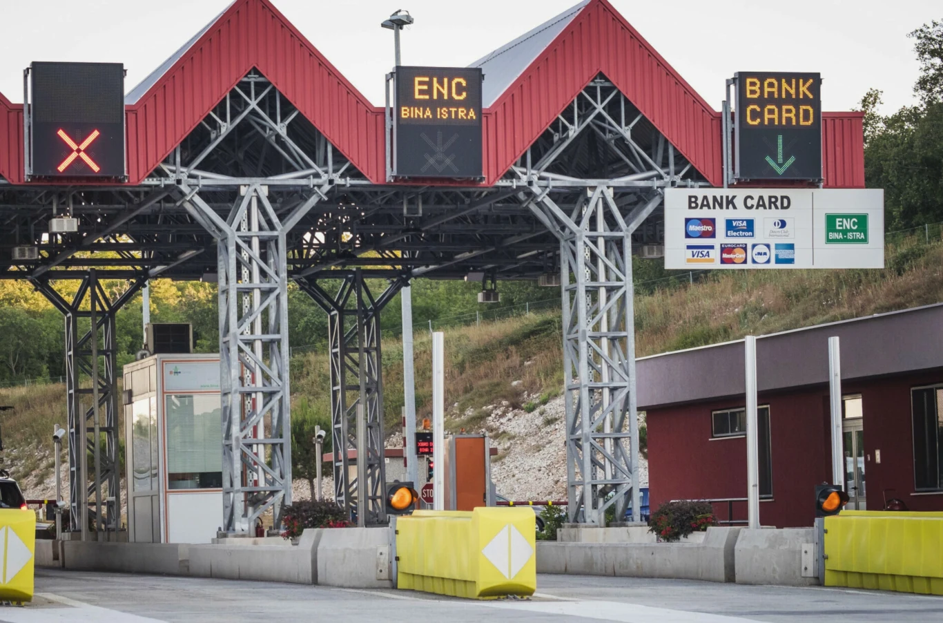 Chorwacja rusza z nowym systemem opłat na autostradach. Bramki płatnicze na autostradzie umożliwiające opłacenie przejazdu za pomocą karty płatniczej lub systemu ENC, widoczna infrastruktura drogowa oraz oznakowanie kierujące do odpowiednich pasów
