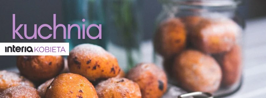 Okrągłe pączki obsypane cukrem pudrem ułożone na stole i w słoiku, w tle rozmyte kwiaty oraz napisy kuchnia i interia kobieta.