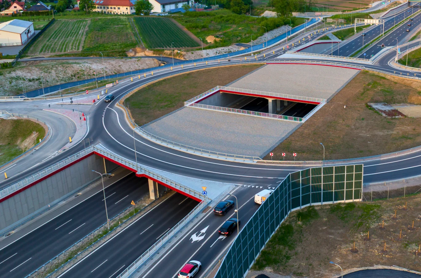Ruch jak nigdy wcześniej. Tunel S52 pod Krakowem przekroczył 2 mln przejazdów. Nowoczesny węzeł drogowy z kilkoma pasami ruchu oraz estakadami, widoczna infrastruktura infrastruktury drogowej, samochody poruszające się po różnych poziomach jezdni, ekrany akustyczne oraz zieleń otaczająca skrzyżowanie.