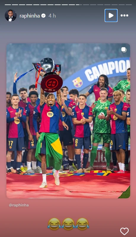 Piłkarz uśmiechnięty trzymający trofeum na scenie, okryty flagą, wokół niego drużyna w sportowych strojach w barwach FC Barcelony, w tle transparent z napisem 'CAMPEONES', atmosfera radości i świętowania.