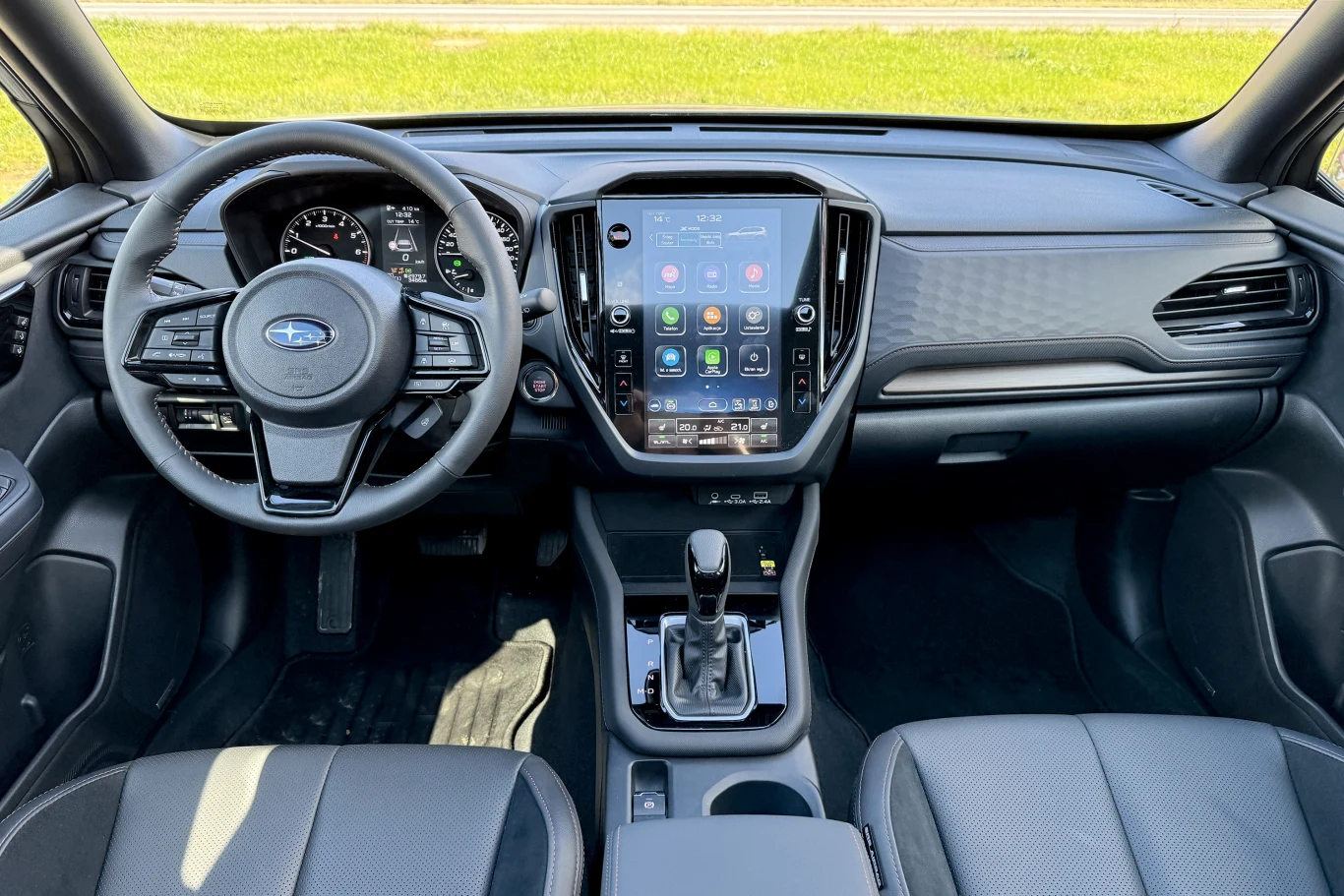 Wnętrze samochodu osobowego Subaru, widoczny kokpit z nowoczesnym, dużym ekranem dotykowym na konsoli centralnej, kierownicą wielofunkcyjną oraz automatyczną skrzynią biegów, skórzane fotele i panele drzwiowe.