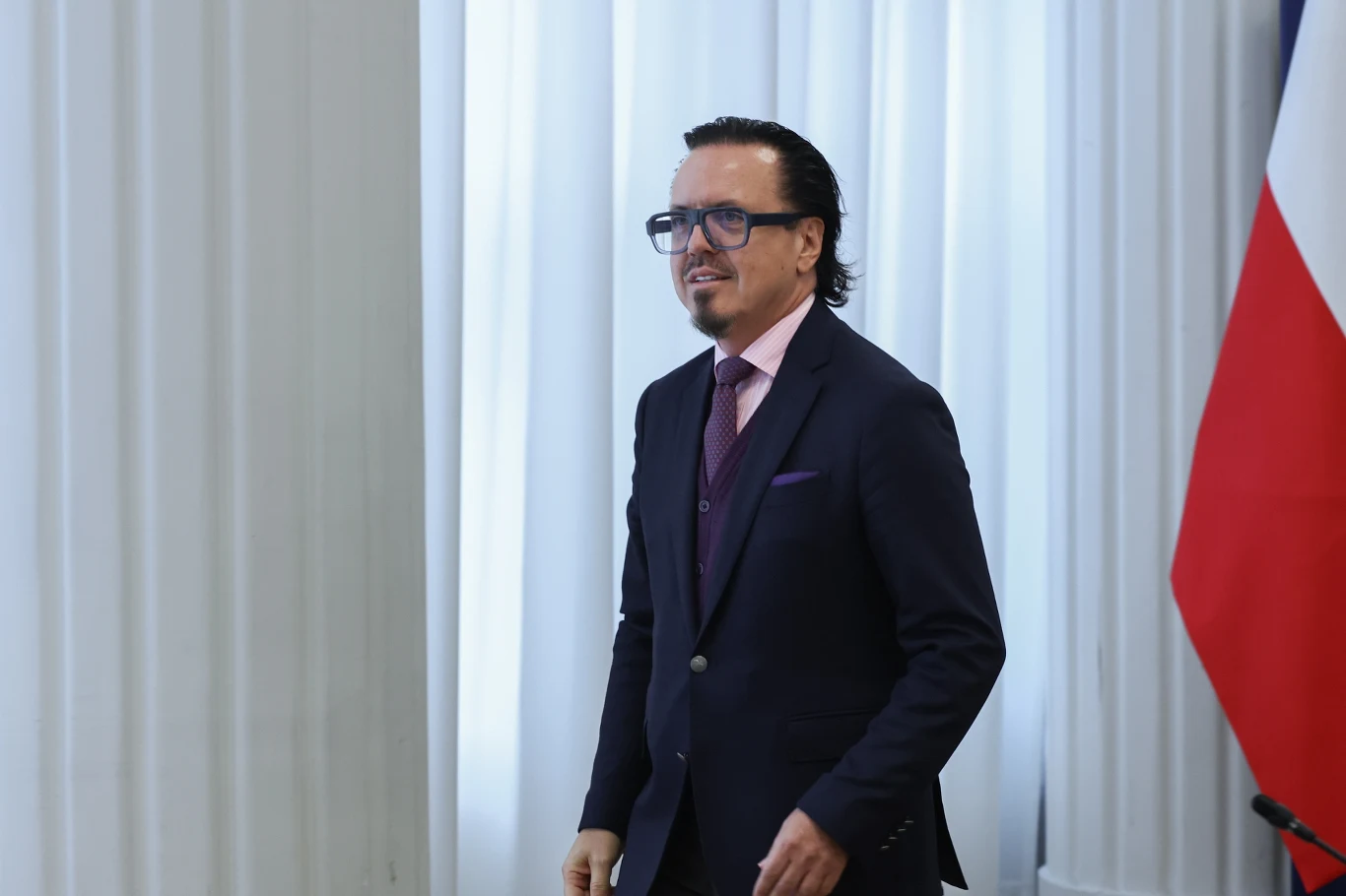 Minister aktywów państwowych Wojciech Balczun zapowiedział, że proces rozliczania nieprawidłowości w spółkach Skarbu Państwa przyspieszy Mężczyzna w garniturze i okularach stoi na tle białych kolumn i fragmentu flagi.