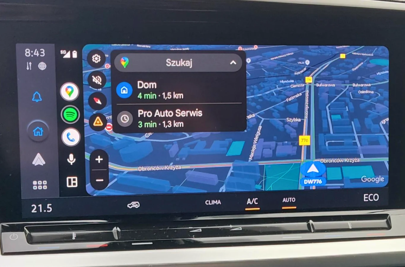 Ekran systemu nawigacji samochodowej wyświetlający trasę do domu oraz do serwisu samochodowego Pro Auto Serwis, widoczne aplikacje na pasku bocznym oraz szczegóły temperatury i klimatyzacji auta.