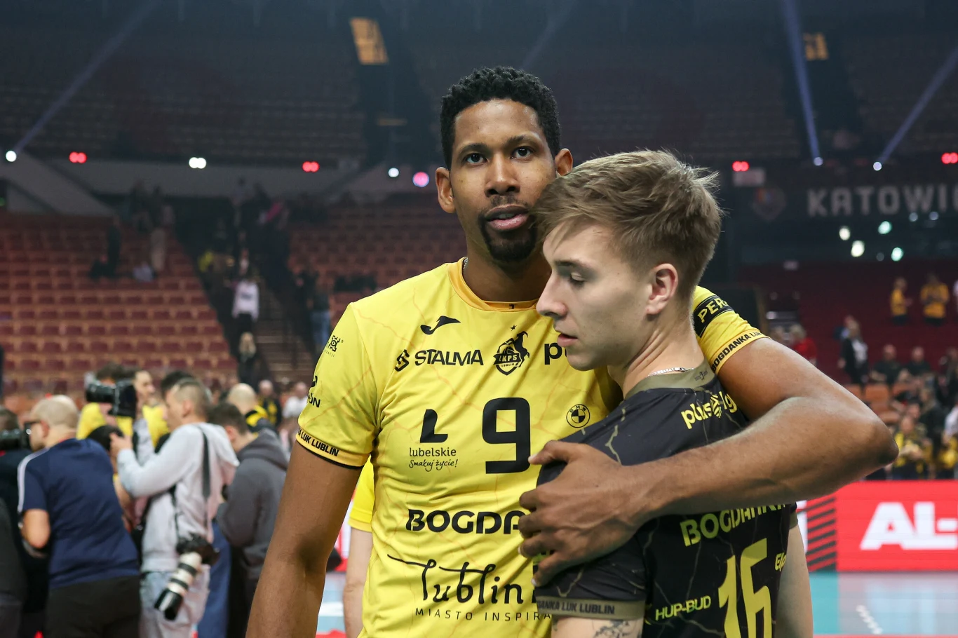 Wilfredo Leon był w meczu o Superpuchar Polski kapitalny. Na zdjęciu z Maciejem Czyrkiem, libero Bogdanki LUK Lublin Dwaj siatkarze w żółtych koszulkach drużynowych obejmują się na parkiecie hali sportowej, w tle widoczni są inni zawodnicy oraz trybuny z kibicami.