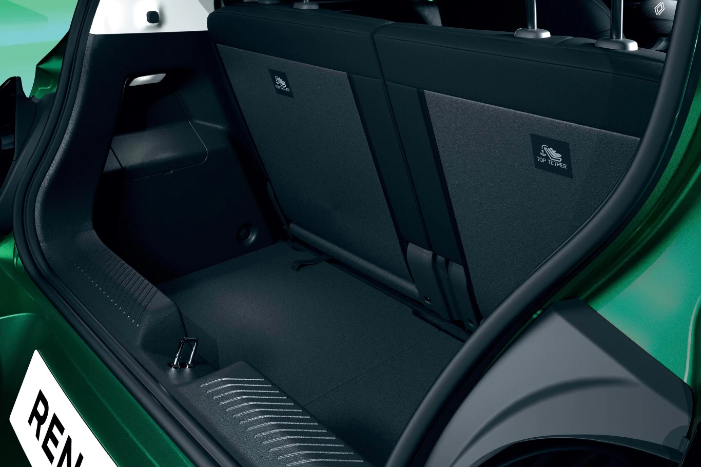 Wnętrze bagażnika zielonego samochodu osobowego z podniesioną tylną klapą oraz widocznymi dwoma złożonymi oparciami tylnych siedzeń, wykończone czarną tapicerką.