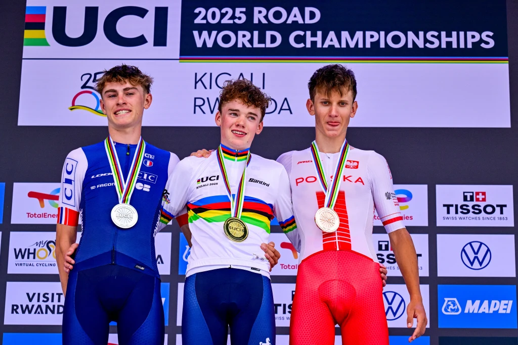 Jan Jackowiak (z prawej) Trzech młodych kolarzy stoi na podium, wszyscy mają medale na szyi. Środkowy zawodnik ubrany jest w tęczową koszulkę mistrza świata i trzyma złoty medal, z lewej strony stoi kolarz w niebieskim stroju z medalem srebrnym, a z prawej zawodnik w biało-cze...