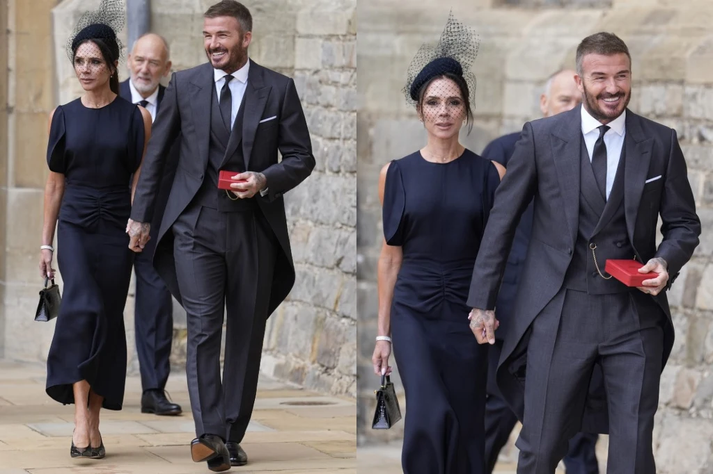 Stylizacja VictoriI Beckham Elegancko ubrana para, kobieta w granatowej sukni i czarnym fascynatorze oraz mężczyzna w klasycznym, ciemnym garniturze z krawatem, trzymają się za ręce i uśmiechają idąc kamiennym chodnikiem w otoczeniu innych osób.