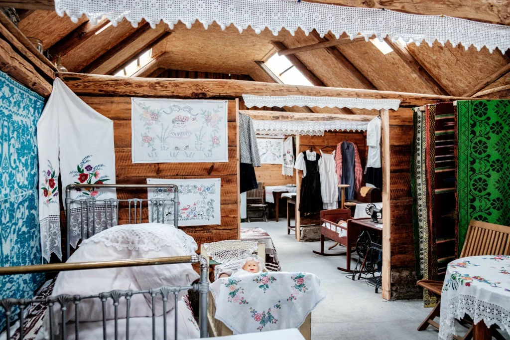 W Muzeum wsi Soce czekają sale z różnorodnymi ekspozycjami Tradycyjne wnętrze drewnianej izby z ręcznie haftowanymi obrusami, zasłonami i pościelą, dziecięcym łóżeczkiem, starodawnymi meblami oraz ludowymi strojami zawieszonymi na wieszakach.