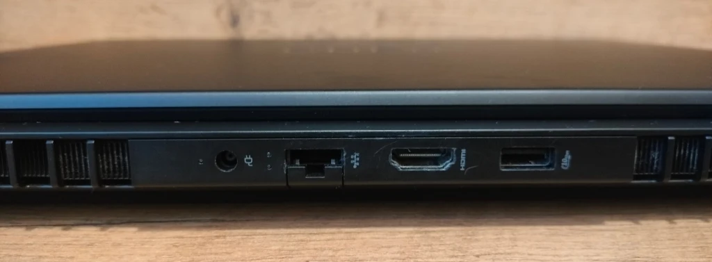 OMEN MAX 16 Boczna krawędź laptopa z widocznymi portami, w tym wejściem słuchawkowym, portem ethernetowym, HDMI i USB, na tle drewnianego blatu.