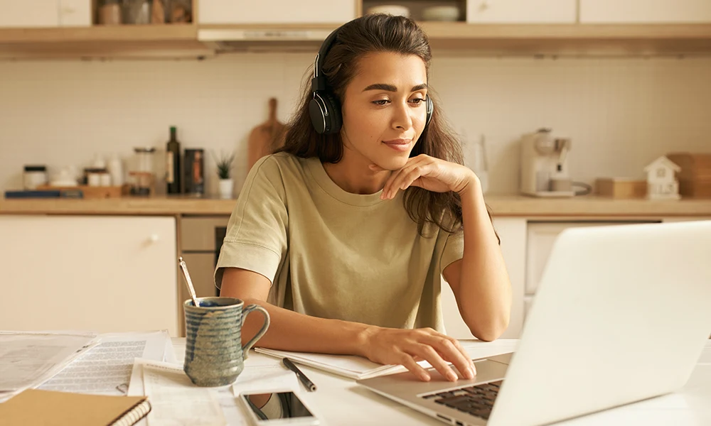PremiumMobile podąża za nowoczesnymi technologiami, by jak najlepiej odpowiadać na twoje potrzeby Kobieta pracująca przy komputerze w kuchni.