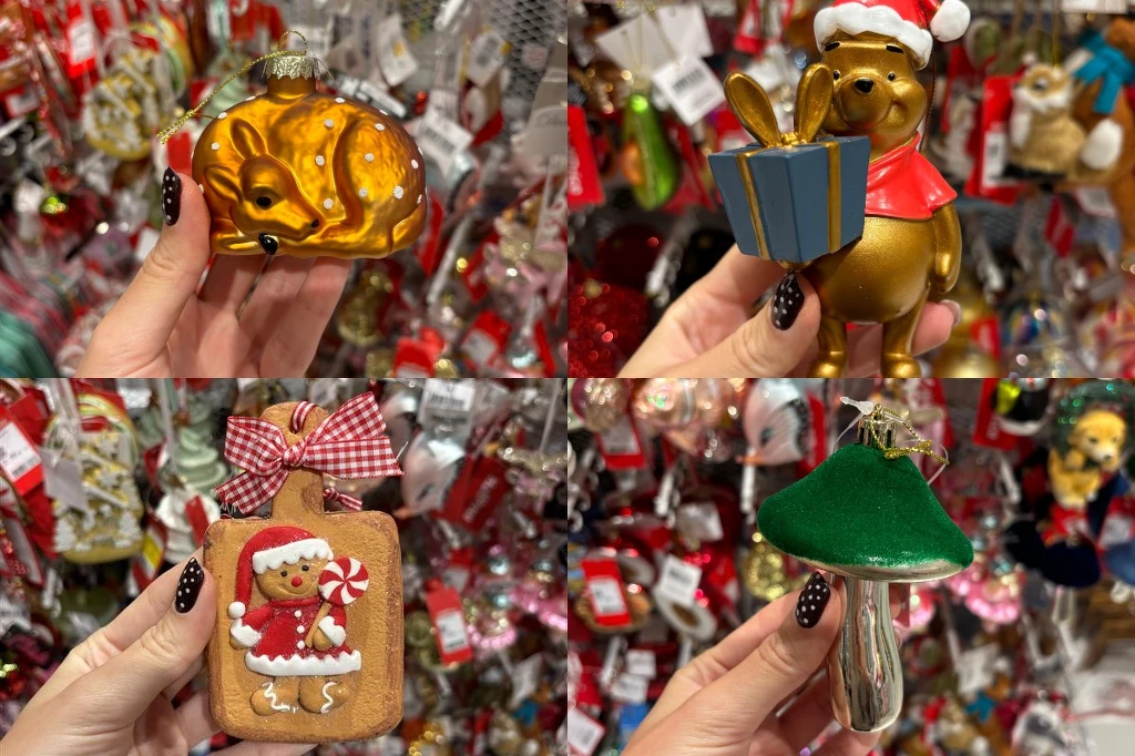 Dekoracje świąteczne TK Maxx W dłoniach trzymane są różnorodne ozdoby choinkowe, takie jak szklana wiewiórka, postać misia w świątecznym stroju z prezentem, dekoracja w kształcie pierniczka oraz grzybka. W tle widoczne są półki z licznymi innymi ozdobami świątecznymi.