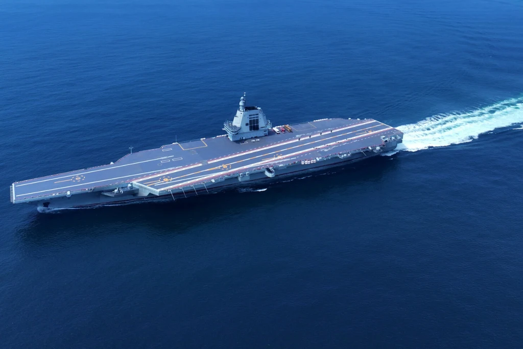 Chiński lotniskowiec "Fujian" wszedł do służby Lotniskowiec płynący po otwartym morzu z widocznym pokładem startowym i nadbudówką, fale tworzą ślad za statkiem na spokojnej wodzie.