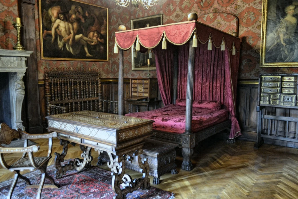 W czasie renowacji zamku udało się odtworzyć jego dawne komnaty Zabytkowa sypialnia z ozdobnym, drewnianym łożem z baldachimem pokrytym czerwonym materiałem, bogato rzeźbionym stołem, antycznymi krzesłami oraz licznymi obrazami w złoconych ramach zawieszonymi na ścianach. Drewniana podłoga i wzorzysta tapeta dopełn...