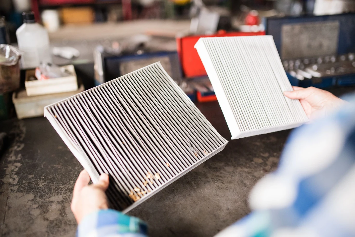 Gdzie znajduje się filtr kabinowy i jak go wymienić? Porównanie dwóch filtrów kabinowych do samochodu, jeden z nich jest zabrudzony, a drugi nowy i czysty. Na brudnym filtrze widoczne są resztki oraz drobiny, natomiast czysty filtr nie nosi śladów użytkowania. Oba filtry trzymane są przez osobę ubraną w ...