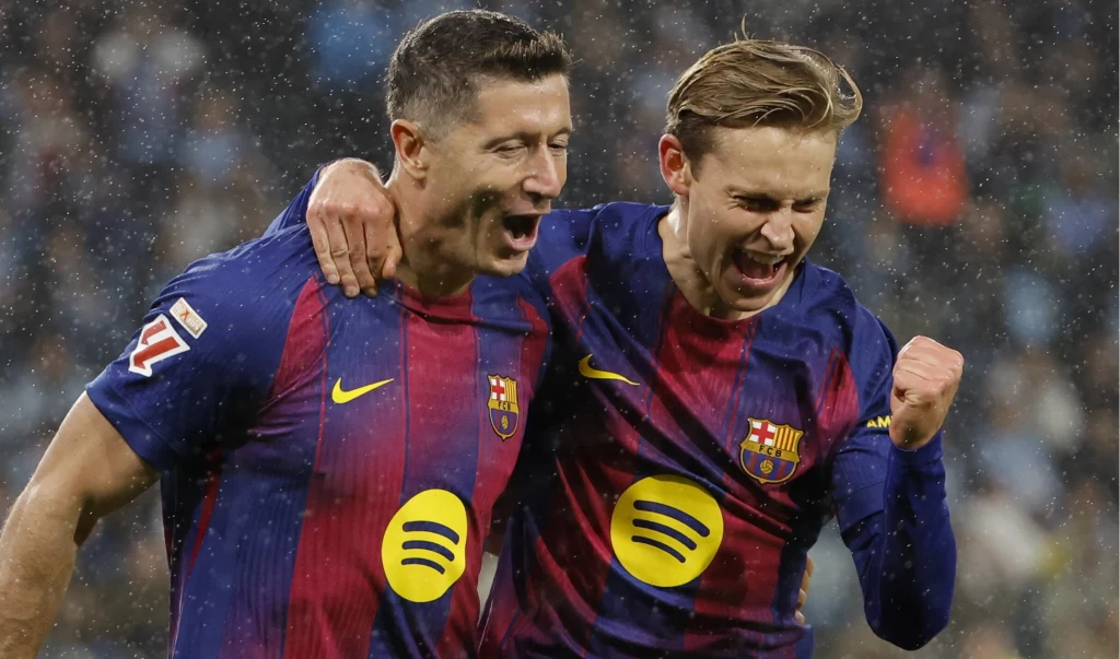 Dwóch piłkarzy FC Barcelony w granatowo-bordowych koszulkach świętuje zdobycie bramki na boisku, obejmując się i wyrażając radość.