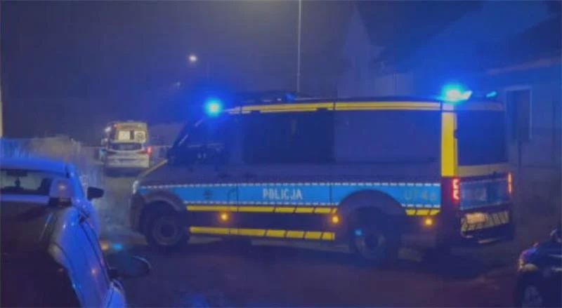 W Pobiedziskach pod Poznaniem policjant zastrzelił 39-latka, który zaatakował nożem funkcjonariuszkę Radiowóz policyjny z włączonymi sygnałami świetlnymi stoi na ulicy w nocy, w tle widać inny pojazd służb i fragmenty zabudowań mieszkalnych, atmosfera sugeruje prowadzenie akcji lub interwencji służb.