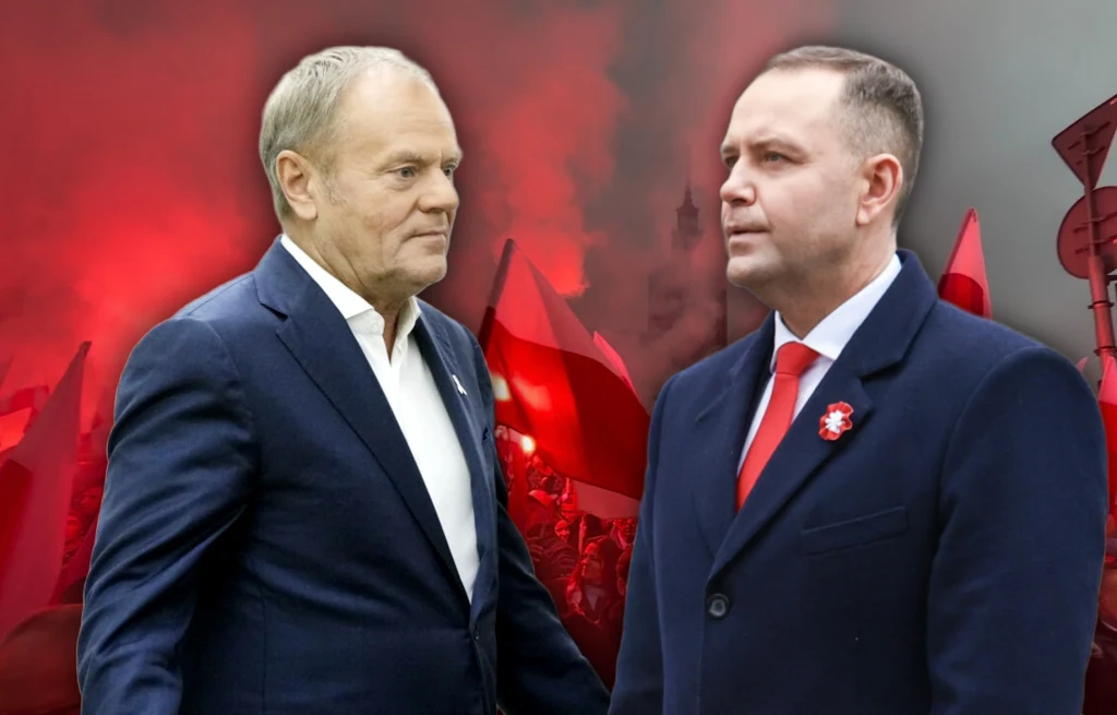 Dwóch mężczyzn w garniturach stoi naprzeciw siebie na tle tłumu ludzi z biało-czerwonymi flagami oraz dymu z rac, motywem dominuje atmosfera polityczna lub manifestacyjna.