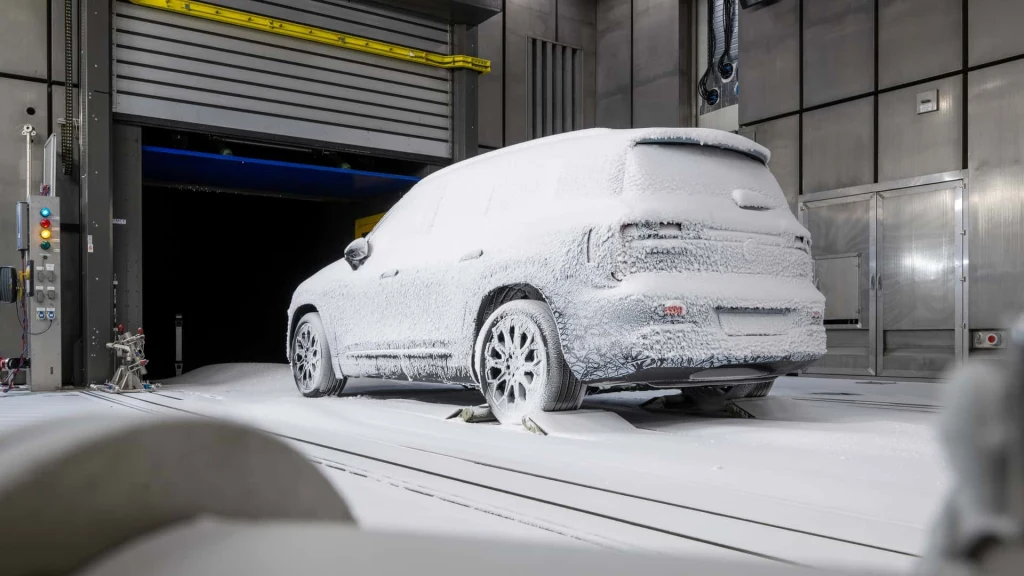 Sylwetka pojazdu nie różni się wiele od poprzedniczki Samochód osobowy całkowicie pokryty grubą warstwą sztucznego śniegu znajduje się w nowoczesnym, przemysłowym pomieszczeniu badawczym, co sugeruje przeprowadzanie testów w ekstremalnych warunkach pogodowych.