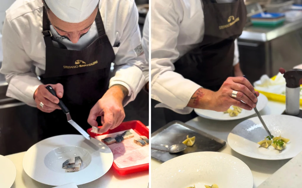 Chef Mateo Tonin jak sam mówi gotuje morze Szef kuchni w białym fartuchu dekoruje talerze z daniem, używając pęsety i noża. Na stole widoczne są składniki, takie jak ryba pokrojona na kawałki i makaron, znajdujące się na białych talerzach i w czerwonej tacce.