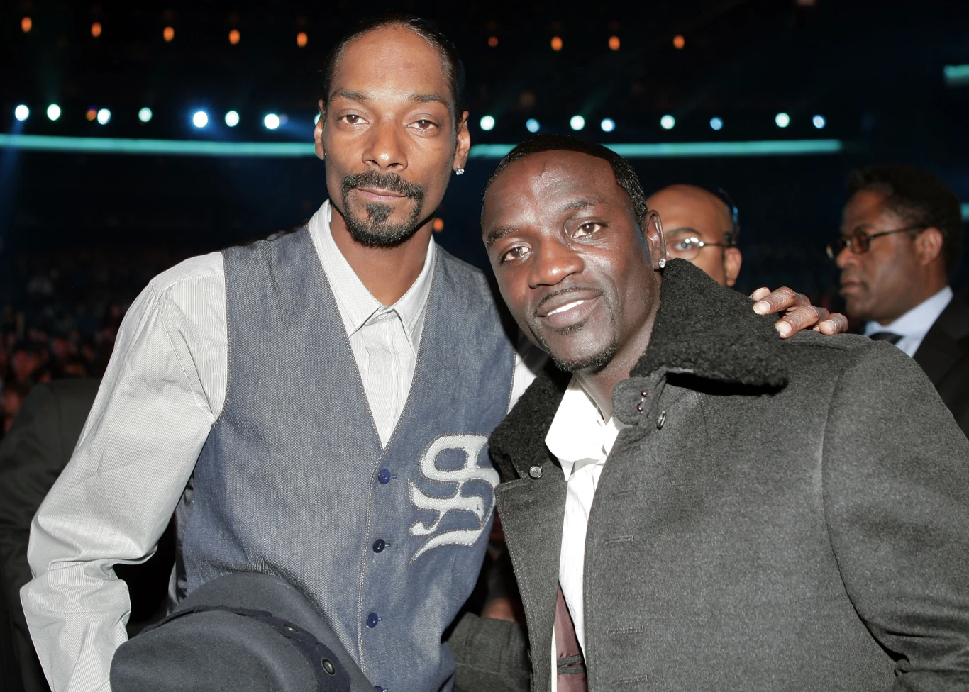 Akon współpracował ze Snoop Doggiem na początku lat 2000. Dwóch mężczyzn elegancko ubranych pozuje razem do zdjęcia, w tle rozmazane światła oraz inne osoby.