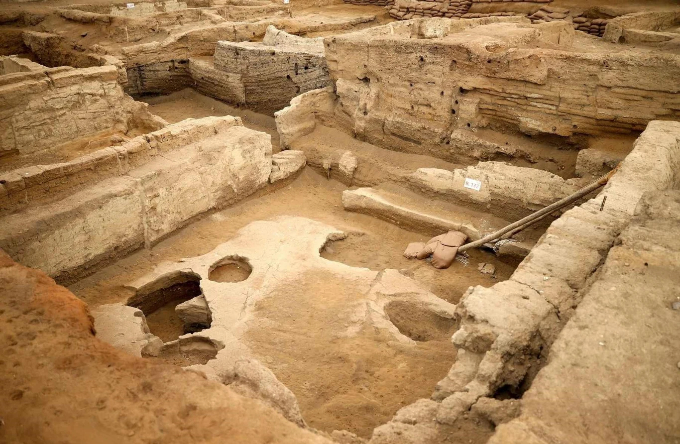Wpisane na listę światowego dziedzictwa UNESCO stanowisko Çatalhöyük to jedno z najstarszych osiedli ludzkich na świecie. Wykopaliska archeologiczne z wyraźnie widocznymi warstwami ziemi i odsłoniętymi fragmentami dawnych murów; w centrum znajdują się narzędzia archeologiczne oraz niewielkie zagłębienia w ziemi, wskazujące na prace badawcze.