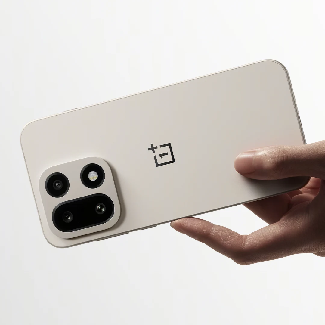 Biały smartfon marki OnePlus trzymany poziomo w jednej dłoni na jasnym tle, z wyeksponowanym modułem aparatu z trzema obiektywami oraz charakterystycznym logo producenta.