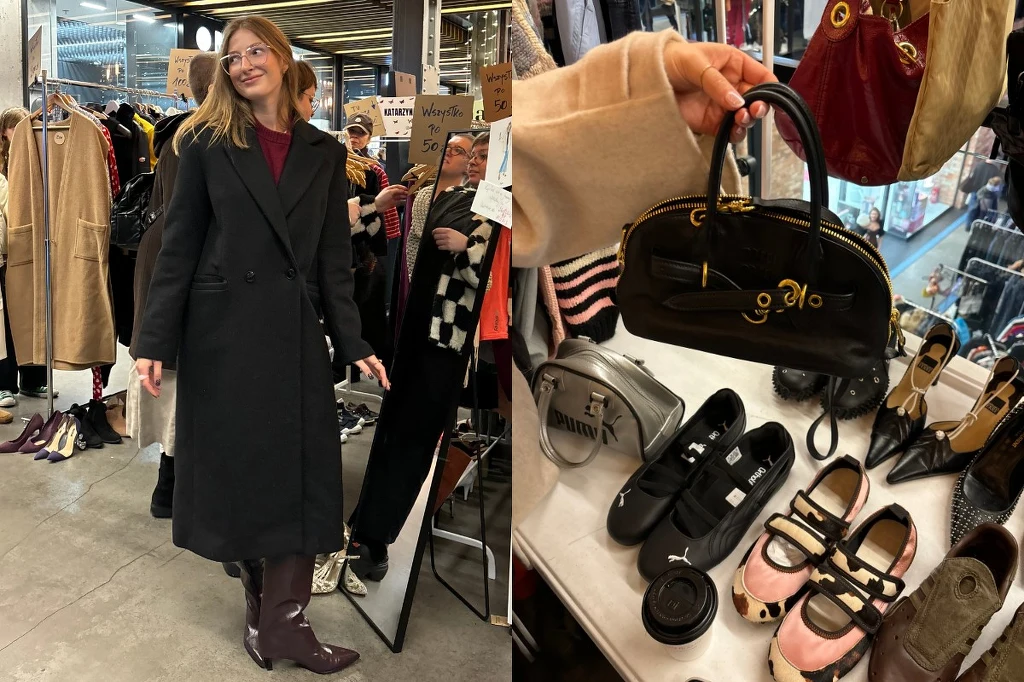 Kobieta ubrana w długi, czarny płaszcz przymierza ubranie w otoczeniu ubrań wiszących na wieszakach, obok znajduje się stolik z akcesoriami i butami, na którym prezentowana jest czarna torebka.