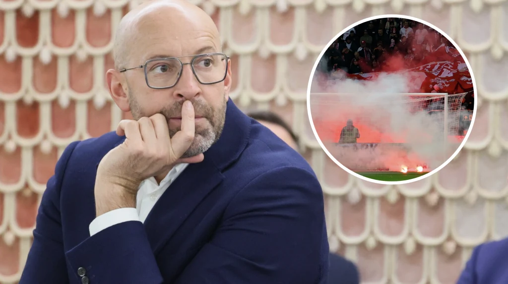 Mężczyzna w okularach i garniturze z zamyślonym wyrazem twarzy, opierający dłoń o usta, na tle ozdobnej ściany; w okrągłym wstawieniu scena stadionowa z pirotechniką, dymem oraz tłumem kibiców za bramką.