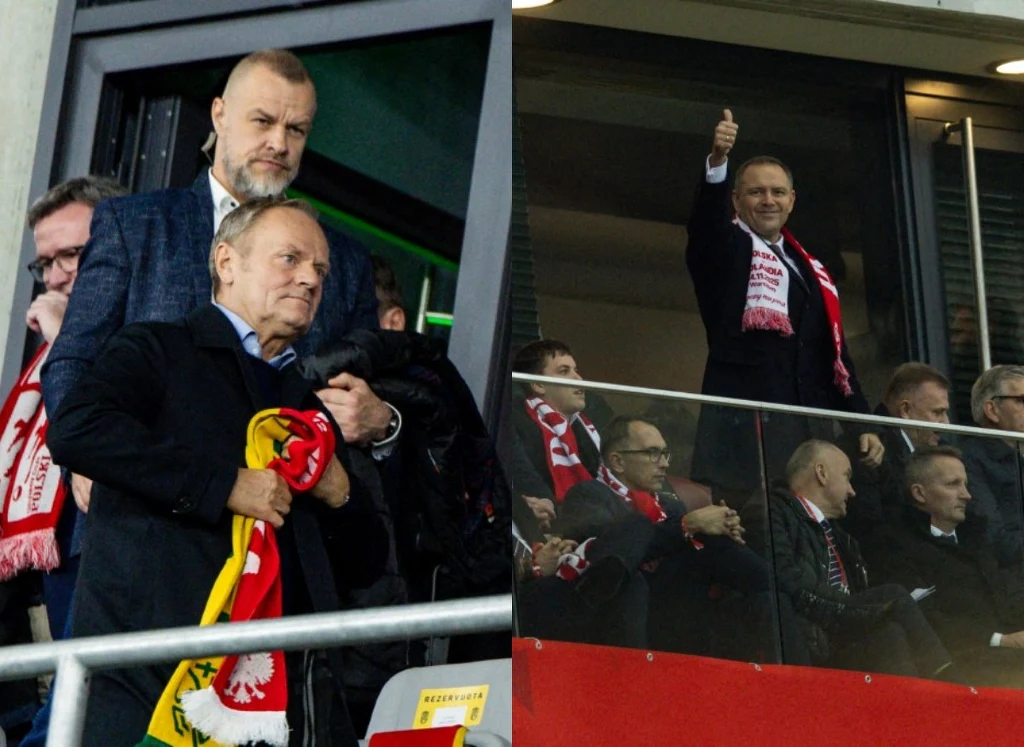 Grupa mężczyzn w loży VIP na stadionie, niektórzy z nich noszą szaliki kibica w polskich barwach narodowych. Jeden mężczyzna pokazuje uniesiony kciuk, pozostali koncentrują się na wydarzeniu na stadionie.