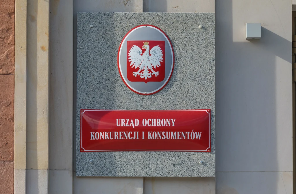 Tablica urzędowa Urzędu Ochrony Konkurencji i Konsumentów z godłem Polski umieszczona na zewnętrznej ścianie budynku administracyjnego.