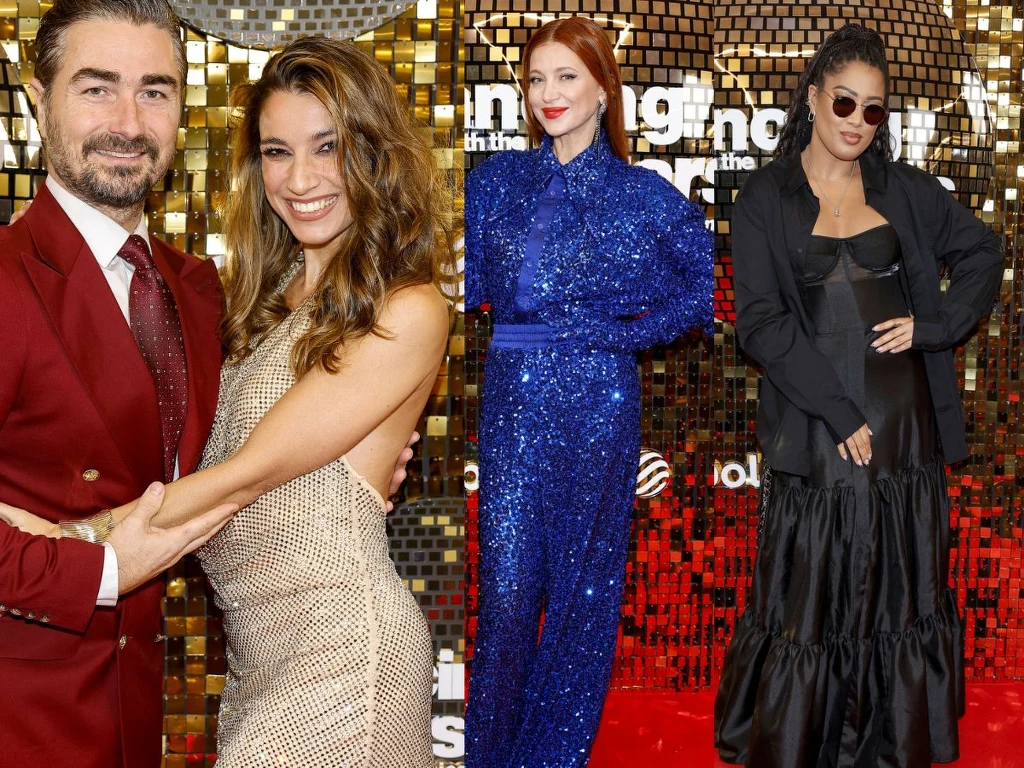 Na ściance "Tańca z gwiazdami" nie zabrakło gwiazd. Oto jak zaprezentowali się Jan Kliment z żoną, Ada Fijał oraz Patricia Kazadi Cztery elegancko ubrane osoby pozujące na tle złotej, błyszczącej ścianki eventowej. Mężczyzna w bordowym garniturze stoi obok kobiety w jasnej sukni. Obok dwie kobiety, jedna w błyszczącym niebieskim kombinezonie, druga w czarnej sukni i okularach prz...