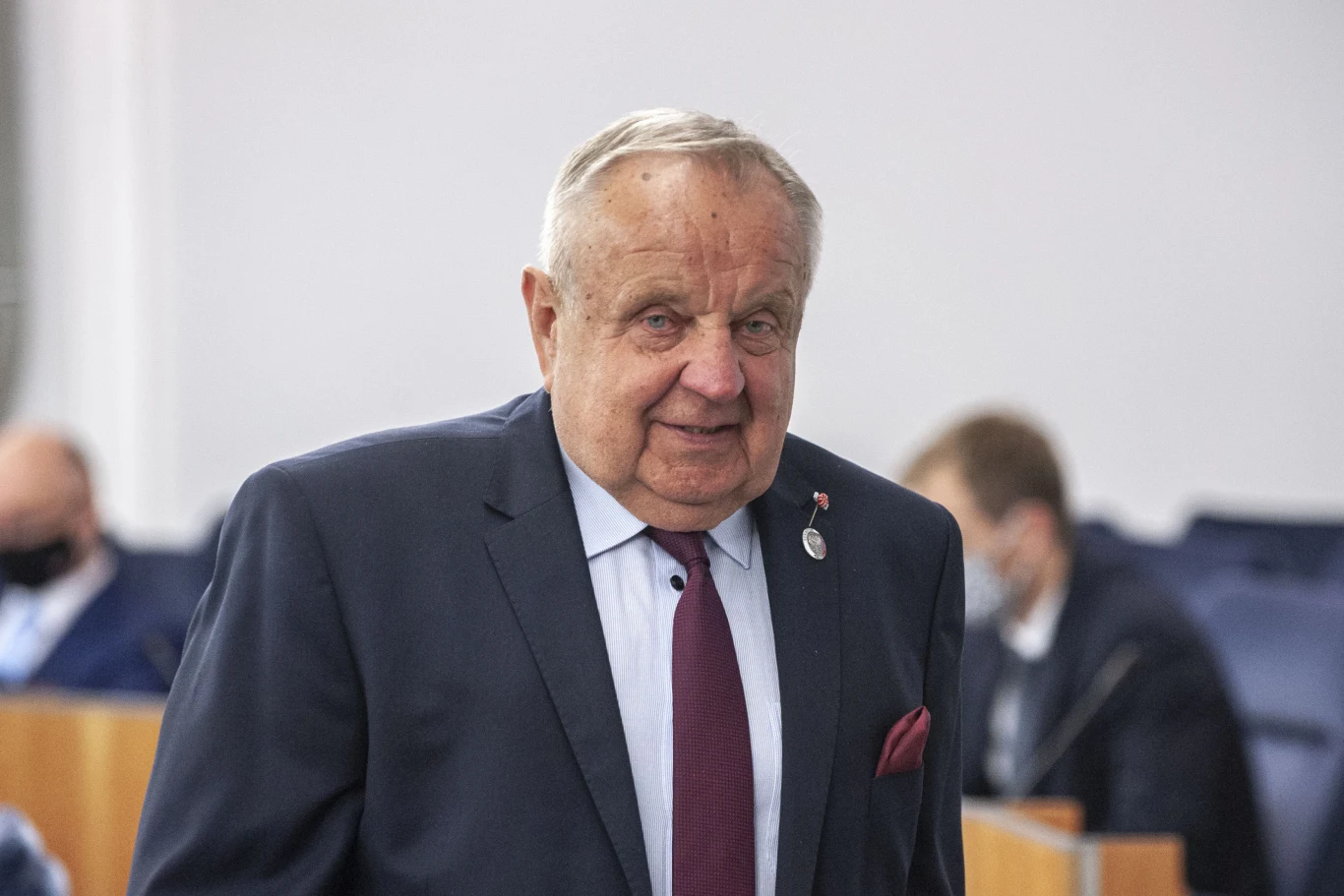 Senator Koalicji Obywatelskiej związany z Gorzowem, Władysław Komarnicki Starszy mężczyzna w garniturze z bordowym krawatem stoi w jasnym pomieszczeniu, w tle widać inne osoby siedzące przy biurkach.