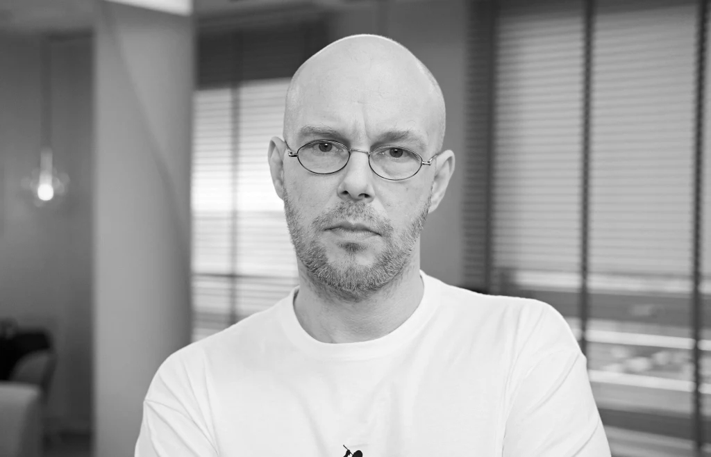 Pono zmarł krótko po swoich 49. urodzinach Łysy mężczyzna w okularach, ubrany w jasny podkoszulek, stoi na tle rozmytego wnętrza z żaluzjami w oknach. Spokojny, poważny wyraz twarzy.