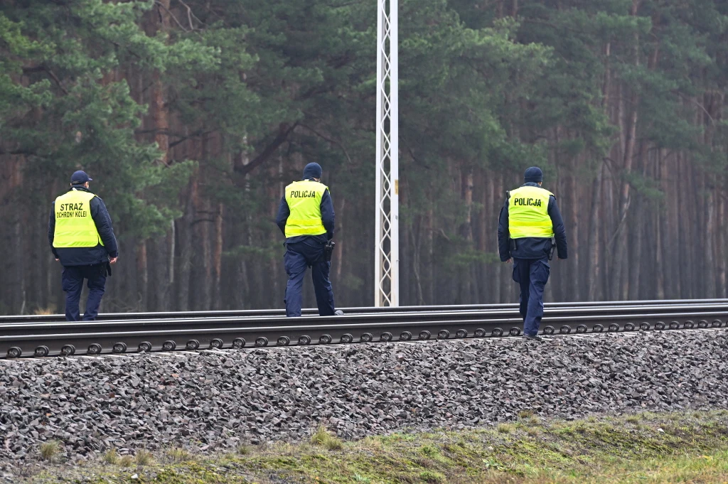 Pod Puławami doszło w niedzielę do zerwania sieci trakcyjnej. Służby nie wykluczają sabotażu Trzech funkcjonariuszy służb mundurowych w odblaskowych kamizelkach patrzących w stronę torów kolejowych, las w tle, szare niebo, spokojna sceneria.