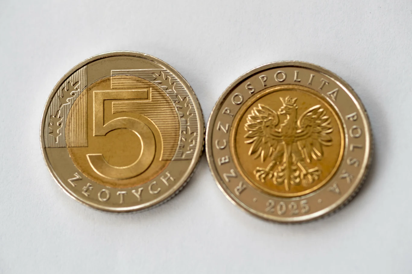 Do obiegu trafi nowe 5 zł. Zdjęcie ilustracyjne Dwie monety o nominale 5 złotych, z jednej strony widoczny duży wytłoczony numer 5, a z drugiej strony orzeł w koronie i napis Rzeczpospolita Polska wraz z rokiem 2025.