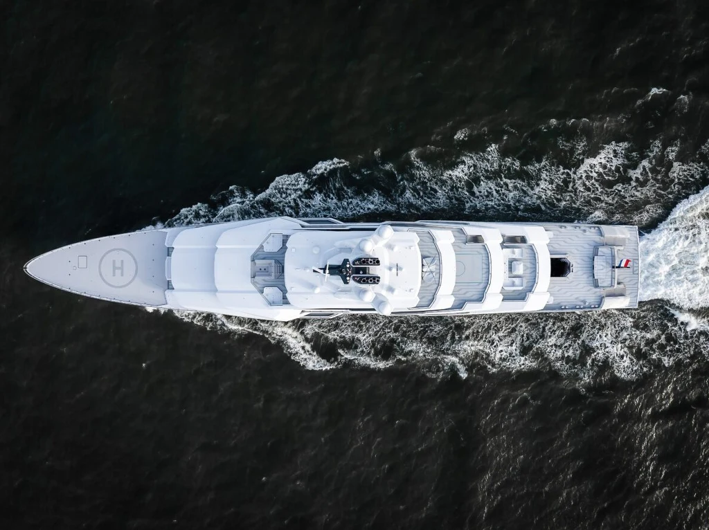 Jacht Leviathan / źródło: oceancoyacht Luksusowy jacht płynący po ciemnych wodach widziany z lotu ptaka, elegancka konstrukcja pokładu, widoczne miejsca rekreacyjne i lądowisko dla helikoptera na dziobie.