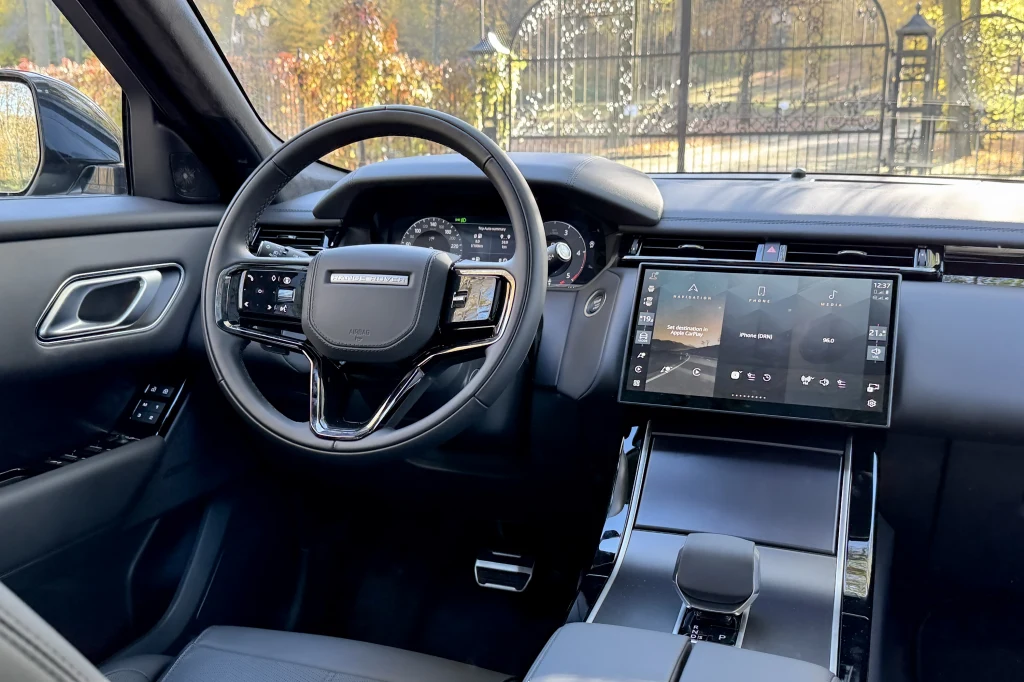 Nowoczesne wnętrze samochodu z kierownicą wykończoną skórą, dużym wyświetlaczem dotykowym na konsoli centralnej oraz eleganckimi, minimalistycznymi elementami deski rozdzielczej.