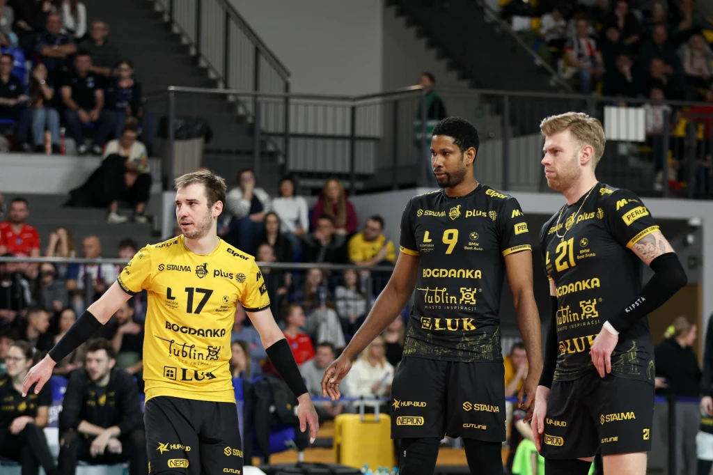 Bennie Tuinstra (z prawej) w poprzednim sezonie wraz z Wilfredo Leonem zdobył mistrzostwo Polski Trzech siatkarzy drużyny w czarno-żółtych strojach podczas meczu, otoczeni kibicami obserwującymi wydarzenie na trybunach.